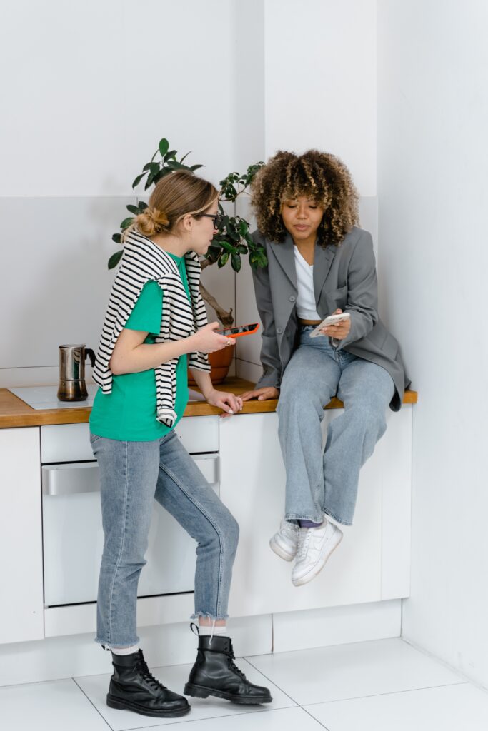 foto-duas-mulheres-uma-branca-uma-preta-na-cozinha-olhando-seus-celulares